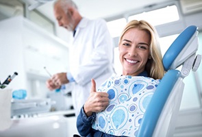 woman giving thumbs up in dental chair 