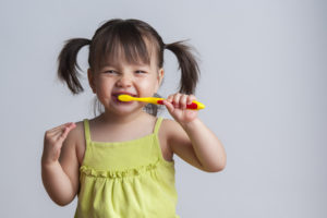 little girl smiling and brushing teeth