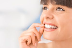 woman smiling inserting Invisalign tray